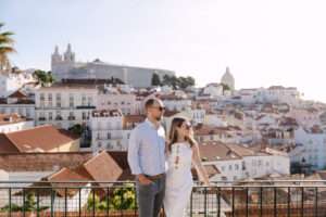 Engaged couple at Miradouro das Portas do Sol overlooking Alfama rooftops Lisbon, save the date photos Portugal