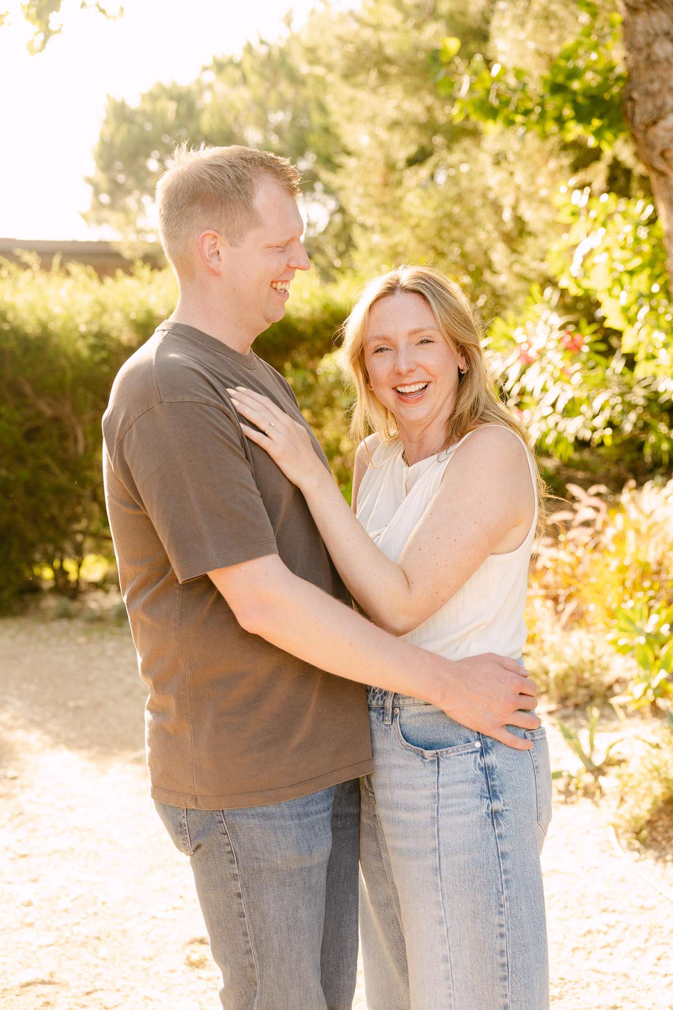 Couple laughing and embracing in Comporta villa garden at golden hour, joyful family holiday photography Portugal