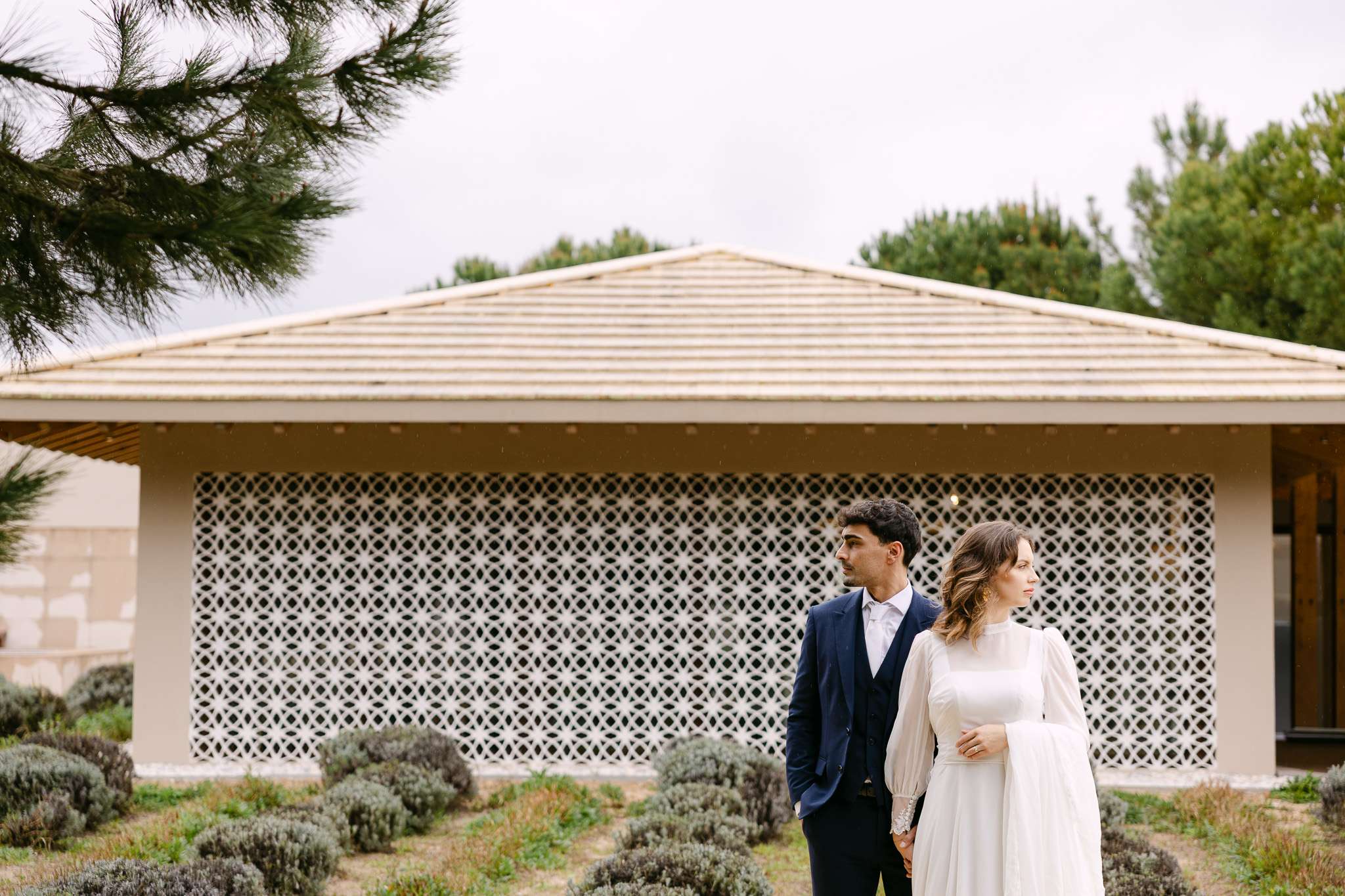 Bride and groom portrait by a Comporta wedding photographer in front of decorative lattice pavilion.