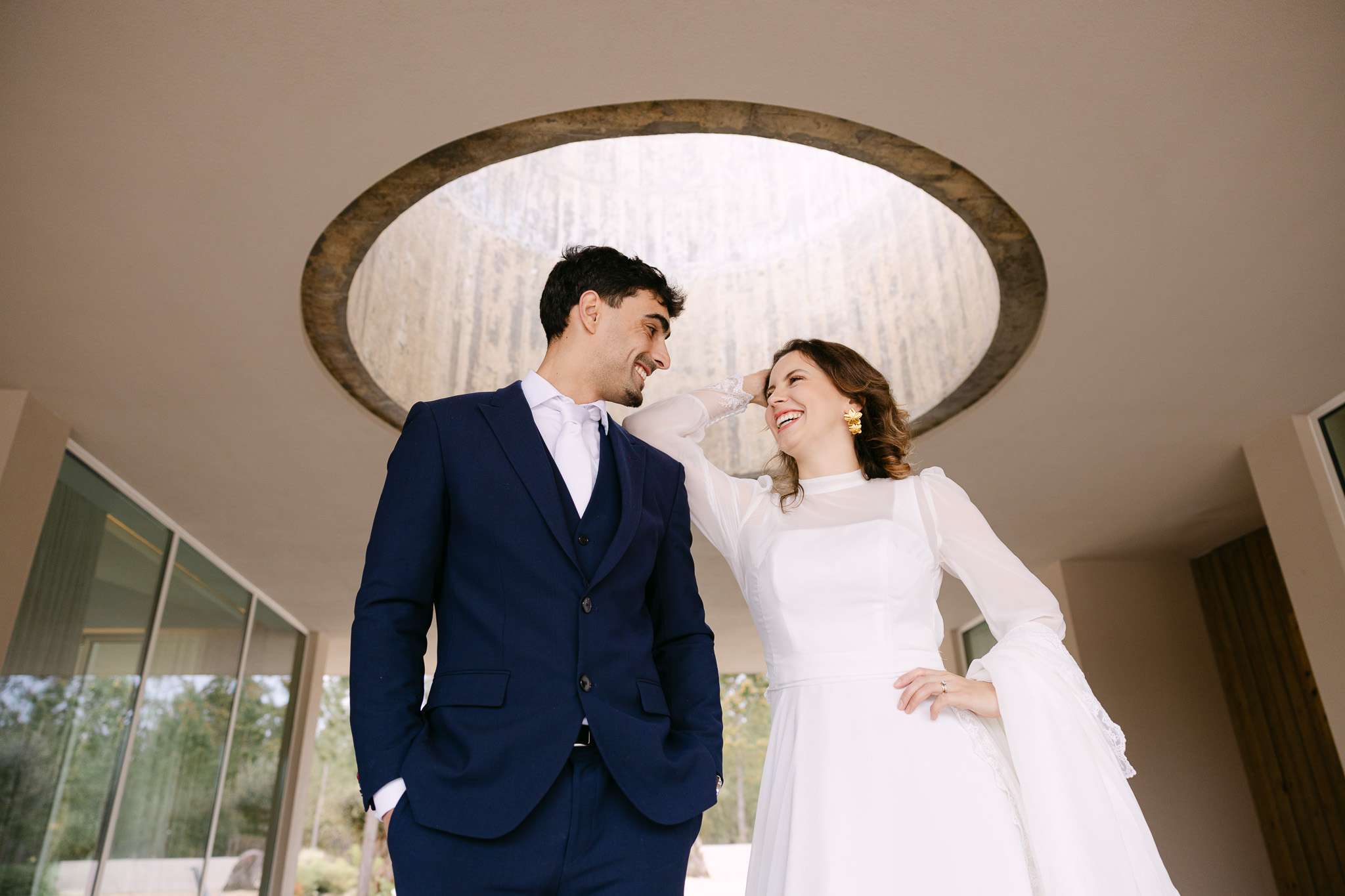 Comporta wedding photography of bride and groom laughing under a circular skylight.
