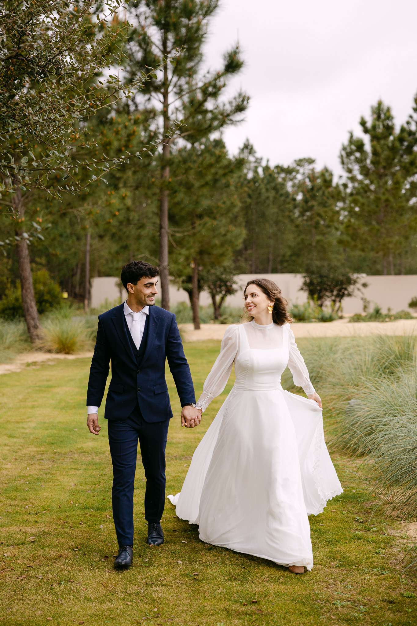 Comporta wedding photographer photo of bride and groom smiling at each other while walking across the grass.
